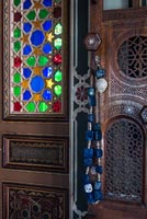 Decorative beads on ornate wooden door with colourful stained glass window