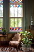 Small stripy armchair next to stained glass window in classic living room
