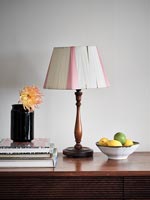Pink and white lampshade on wooden sideboard 