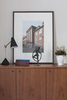 Framed photograph of a building on wooden sideboard 
