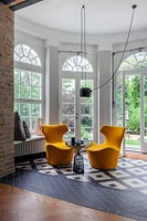 Pair of orange chairs in living room with monochrome flooring 