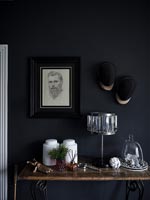 Artwork on black painted wall above console table decorated with ornaments 