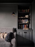 Grey sofa and wooden unit in dark painted living room 