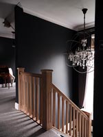 Wooden staircase with black painted walls and modern chandelier 