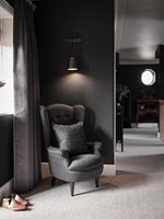 Grey armchair in black painted modern hallway 