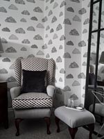 Black, white and grey armchair in modern bedroom with cloud wallpaper 