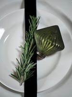 Green bauble and sprig of rosemary on plate for Christmas 
