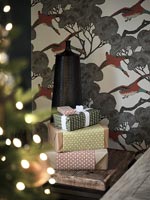 Wrapped Christmas gifts on side table next to patterned wallpaper 