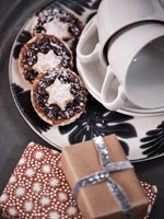 Mince pies on plate with tiny wrapped Christmas gifts 