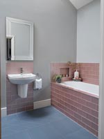 Modern bathroom with dusky pink tiling around bath and sink 