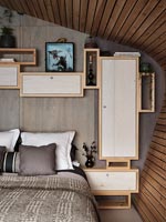 Modern bedroom with network of wall mounted wooden storage cupboards 