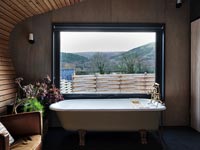 Bath next to window in modern bedroom with scenic views 