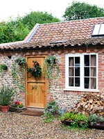 Exterior of small country cottage with decorative wreath on front door 