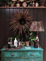 Feather wreath above painted chest of drawers 