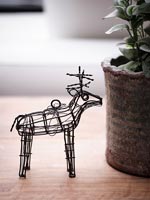 Reindeer ornament next to potted houseplant on side table 