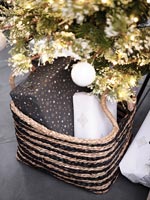 Black and gold Christmas gifts in basket under tree 