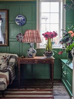 Flowers and lamp on antique side table in colourful classic living room 