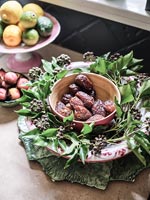 Bowl of dates decorated with ivy foliage and flowers 