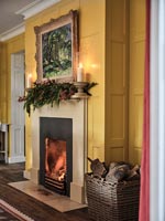Christmas garland and candles on mantelpiece of lit fireplace 