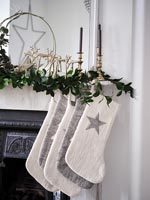 Cream and grey Christmas stockings hanging on mantelpiece 