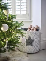 Basket of Christmas crackers next to tree 