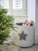 Basket of Christmas crackers next to tree 