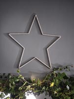 Silver star against grey painted wall with ivy garland Christmas decoration