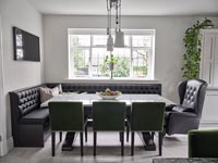 Upholstered corner bench and leather armchair seating in modern dining room