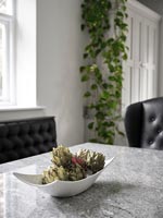 Artichokes in white bowl on grey marble table 