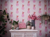 Painted unit and houseplants in bathroom with pink pineapple wallpaper 