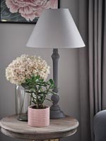 House plant and flowers next to lamp on round side table 