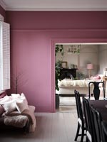 Pink painted walls in modern dining room  with small sofa 