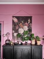 Black painted wooden sideboard next to pink wall 