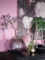 Branch with black seed heads in purple vase on mantelpiece 