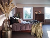 Ornamental grasses in vase in bedroom with dusky pink painted walls 