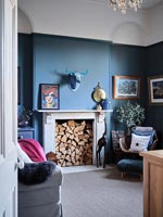 Fireplace filled with logs in modern blue painted living room 
