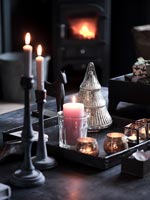 Detail of lit candles and Christmas decorations on coffee table 