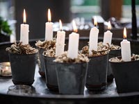Lit candles in tiny pots with decorative moss 