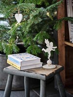 Books and angel ornament next to Christmas tree 