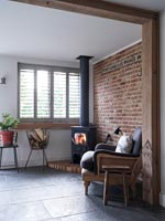 Wood burning stove in corner next to exposed brick wall 