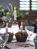 Small candles in moss filled star shaped pots on dining table 