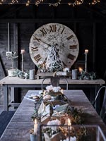 Large clock, Christmas decorations and lights around table 