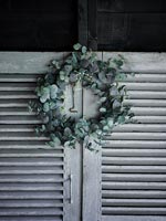 Small green Christmas wreath on grey painted wooden slatted doors 