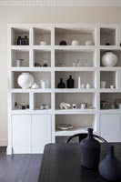 Black and white ceramics displayed on large unit in modern dining room 