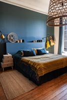 Dark blue painted walls and headboard in modern bedroom 