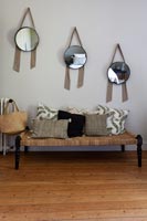 Row of matching mirrors above wicker bench seat with cushions 