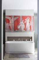Colourful artwork above bath in modern bathroom 