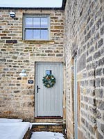 Christmas wreath on front door of country house in snow 