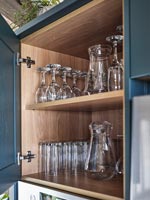 Open kitchen cabinet door with shelves of glasses 