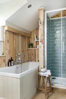 Modern country bathroom with wooden panelling on wall above bath